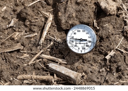 Soil thermometer in soil of farm field. Soil temperature, planting season and farming weather forecast concept.