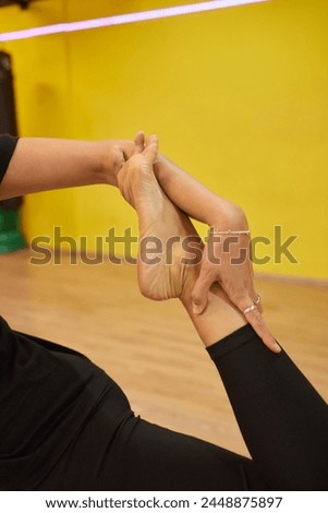 A woman is extending her legs at the gym, displaying signs of flexibility and strength. Her body movements reflect grace and control Royalty-Free Stock Photo #2448875897