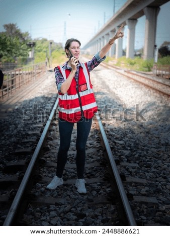 Woman railway engineer use walkie-talkie talking in to talk to maintenance department at site work of train garage. Royalty-Free Stock Photo #2448886621