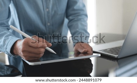 Female designer working, using stylus pen and digital graphic tablet, laptop computer at studio office. Young casual business woman, freelancer standing at desk, online working at home office