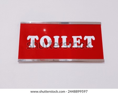 The toilet sign is attached to the white wall