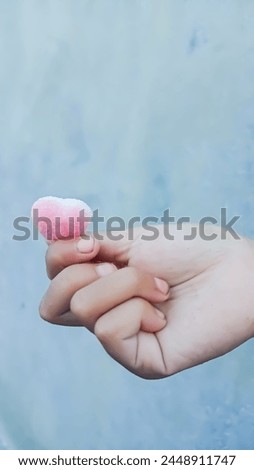 A picture of colorful heart shape pink soft candy in the palm of a child's hand