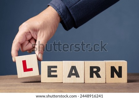 Businessman put another alphabet wood blocks in front of the word. Learn and Earn, self improvement, training, and development concept