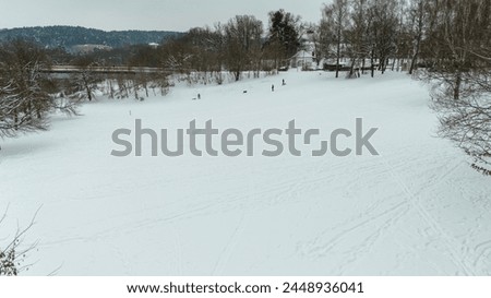 Drone photography of children playing in park with snow during cloudy winter day