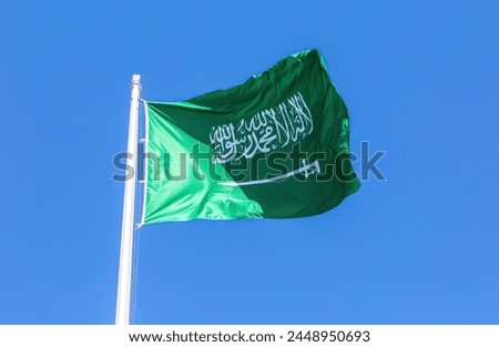 National flag of Saudi Arabia waving in the wind against a blue sky. Saudi Arabia flag blowing in the wind