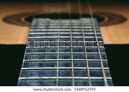 Close up of old acoustic guitar fretboard with selective focus in the center. Neck perspective with blurred sound hole and strings. Music concept Royalty-Free Stock Photo #2448952395
