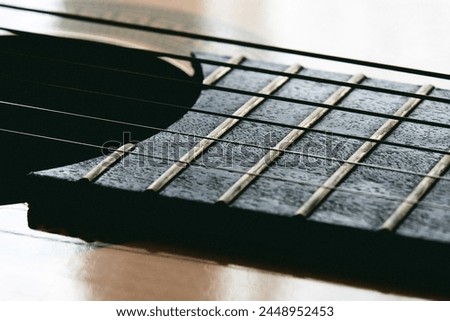 Close up of old acoustic guitar fretboard with selective focus in the center. Neck perspective with blurred sound hole and strings. Music concept Royalty-Free Stock Photo #2448952453