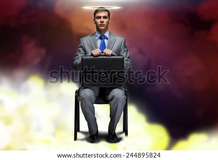 Young businessman with halo above head sitting on chair