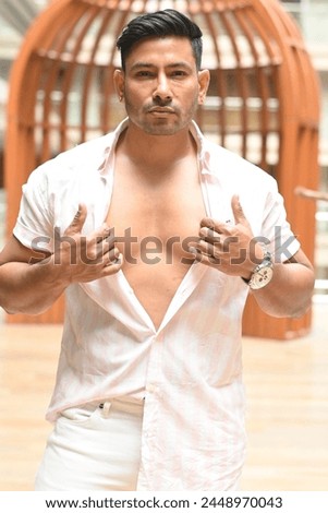 Confident Indian man showcasing his chest, exuding strength and charisma. Ideal for fitness, lifestyle, and masculinity concepts Royalty-Free Stock Photo #2448970043
