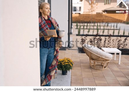 Lady standing and looking ahead when holding book and cup