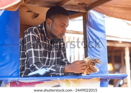 young african point of sale machine attendant standing in a boot