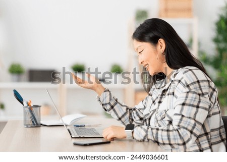 Side view of a young chinese woman talking during an online meeting from home