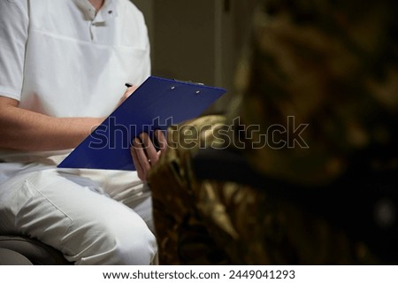 Healthcare professional writing down medical history of military man