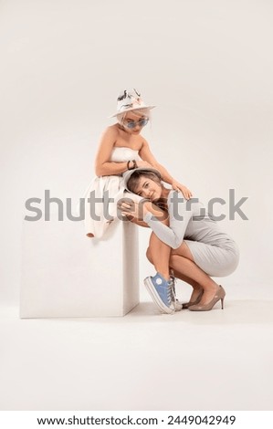 studio photo of two girls in clothes of different styles, acting out application or forgiveness with each other on a white background, parent-child conflict psychology