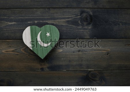 wooden heart with national flag of pakistan on the wooden background. concept