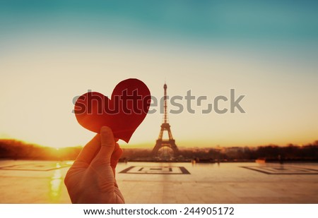 beautiful vintage card from Paris, Eiffel tower and hand with paper heart at sunrise
