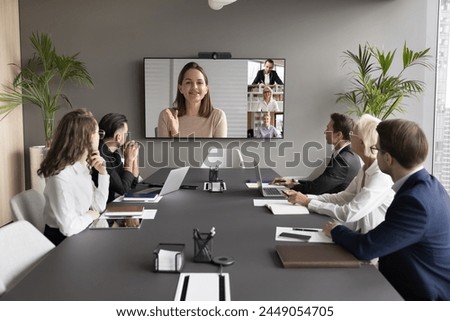 Female leader on screen, provide explanation, informing to teammates at formal virtual meeting. Group of staff listening speech of businesswoman, lead briefing event take part in videocall by business Royalty-Free Stock Photo #2449054705