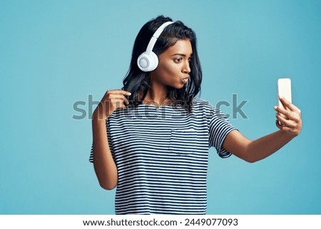 Fashion, music and selfie of woman in studio for social media isolated on blue background. Photography, headphones and Indian girl in casual clothes or influencer listening to kpop on mockup space