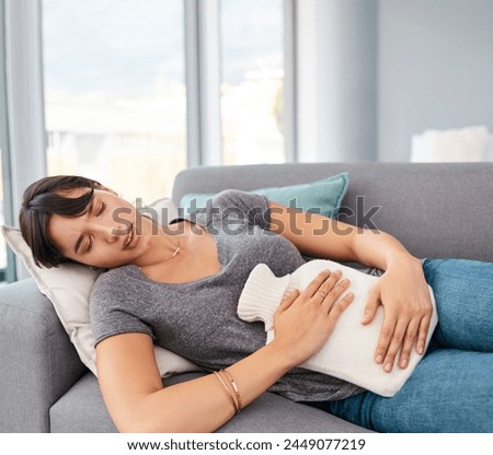 Woman, sofa and pain with hot water bottle in home, abdominal cramps or menstrual issues. Endometriosis, cyst ovaries or uterus problems, resting in living room for comfort or menstruation relief Royalty-Free Stock Photo #2449077219