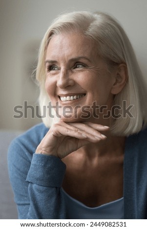 Close up vertical profile picture of satisfied pretty mature woman smiling, revealing perfect white teeth, advertising professional dental clinic services. Optimistic mood, carefree retiree portrait
