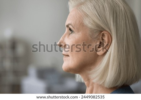 Close up profile picture of serious mature woman looking straight. Side view attractive older female, advertising anti-ageing or rejuvenation procedure, rhinoplasty, plastic surgery clinic services Royalty-Free Stock Photo #2449082535