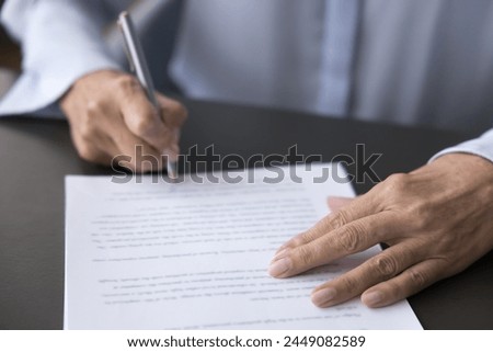 Older female hand signing business document, putting signature on legal paper, making commercial deal or investment, taking bank loan, buying services or insurance, writing testament, close up view Royalty-Free Stock Photo #2449082589