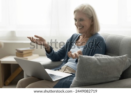 Laughing mature woman enjoy on-line talk with family living abroad using laptop and videoconference application, look at screen, share happy news, lead conversation spend time at home. Videocall event Royalty-Free Stock Photo #2449082719