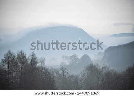 Beautiful layered landscape image of misty Spring morning in Lake District looking towards distant misty peaks