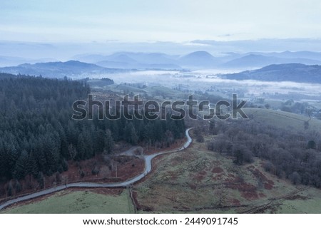 Stunning drone aerial landscape image of cloud inversion around Esthwaite Water in Lake District during Spring sunrise blue hour