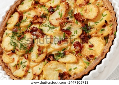 close-up of Irish potato pie of crispy crust layered with potatoes, bacon and onion in baking dish on white wooden table, dutch angle view Royalty-Free Stock Photo #2449105913