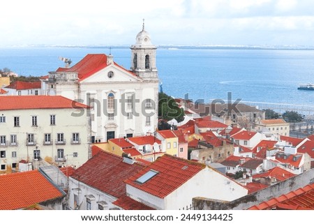 View of historical houses with red roofs, Lisbon, Portugal. Amalfa district. The Miradouro de Santa Luzia viewpoint. The Church of Sao Vicente of Fora in the background. Royalty-Free Stock Photo #2449134425