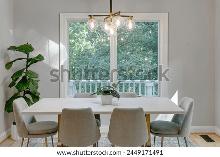 Beautiful Simple Dining Room Interior with A Modern White Table Set, Contemporary Light Fixture and Fiddle Leaf Fig Royalty-Free Stock Photo #2449171491
