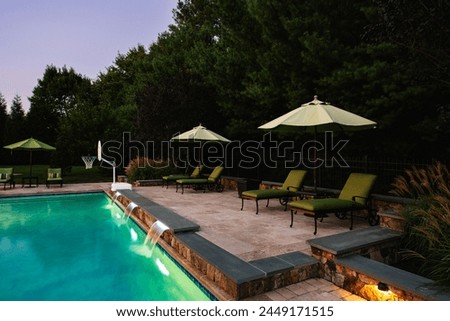 Inviting Pool Area Captured at Twilight, Enhanced by Ambient Lighting and Comfortable Lounge Setting, Built in Waterfall