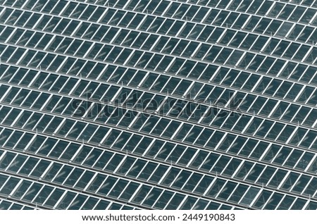 A close up of a building with many windows. The windows are all the same size and are arranged in a grid pattern. The building appears to be a modern structure with a lot of glass Royalty-Free Stock Photo #2449190843
