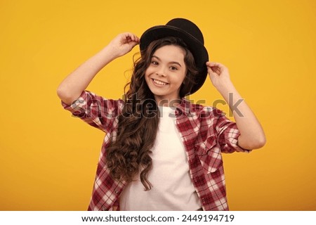 Child teen girl in magician hat, cylinder hat isolated on yellow background. Headwear. Clothes accessories. Fashion headwear for gentlemen in vintage style, old classic cylinder. Royalty-Free Stock Photo #2449194719