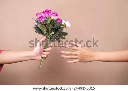 Hand Giving Flower Bouquet and Other Hand Receive It on Woman's Day Celebration Isolated over Brown Background