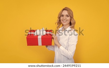 happy woman hold big present box on yellow background