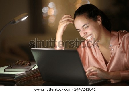 Tele worker in the night laughing checking laptop at home Royalty-Free Stock Photo #2449241841