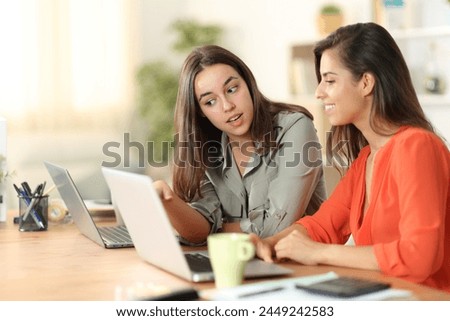 Two tele workers talking about work checking laptop content at home Royalty-Free Stock Photo #2449242583