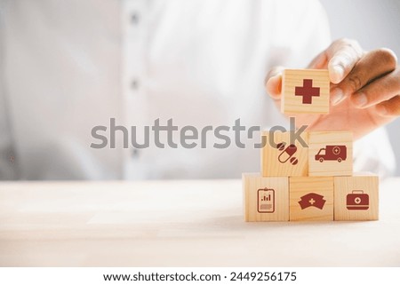 Captured moment, Hand grips wooden block with healthcare and medical icons. Portrays safety, health, and family well-being, symbolizing pharmacy, heart care, and happiness. health care concept
