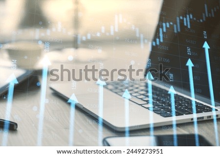 Close up of laptop, smartphone and supplies at desk with growing blue vertical arrows and candlestick forex chart on blurry index grid background. Economic growth and increase concept. Double exposure