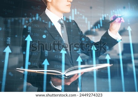 Close up of man holding book and using growing blue vertical arrows and candlestick forex chart on blurry office index grid background. Economic growth and increase concept. Double exposure