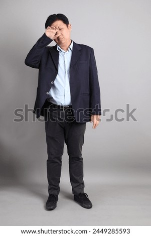 The Asian Businessman with formal dressed with gesture of Sleepy on the gray background.