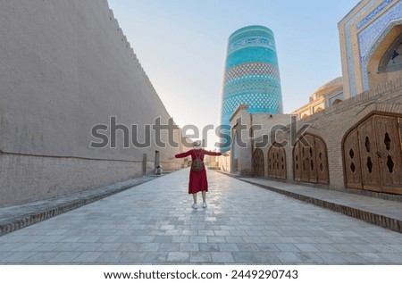 Young lady taking a picture of oriental buildings in Itchan Kala ancient town. Khiva, Uzbekistan