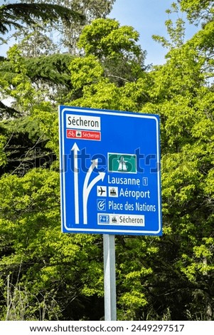 A blue traffic sign in Geneva indicating the direction of the motorway, Lausanne and the airport