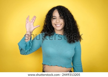 African american woman wearing casual sweater over yellow background doing star trek freak symbol