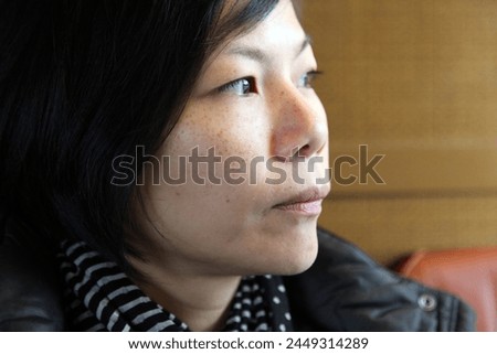 Interior close up photo visual portrait of a younf asian chinese charming pretty beuatiful woman female girl who looks aside with long balck hair and neutral expression face head framing