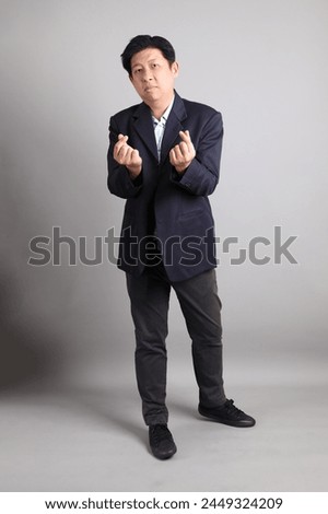 The Asian Businessman with formal dressed with gesture of Heart-shaped, mini heart, love on the gray background.