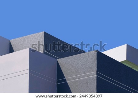 High section of gray and white buildings group in geometric shape with sunlight and shadow on surface against blue clear sky background, Exterior architecture in minimal style Royalty-Free Stock Photo #2449354397