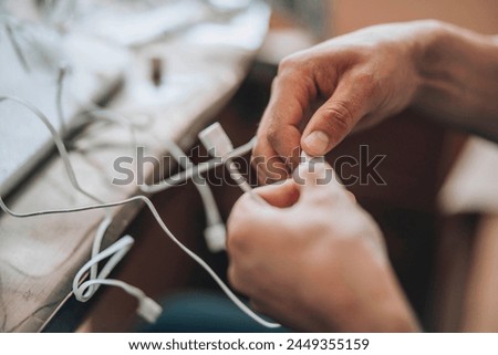  Entangled Solutions - A close-up of hands meticulously selecting the right cable from a tangled assortment, symbolizing the complexity and precision needed in technological troubleshooting